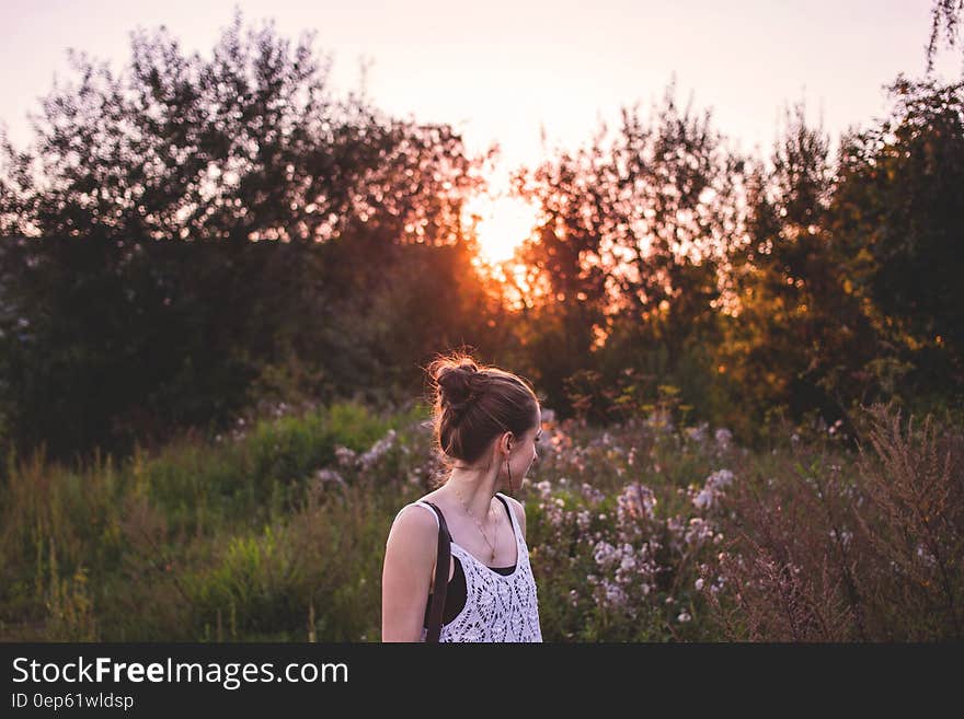 Selective Focus Photography of Woman Standing in the Middle of Grasses and Flowers during Golden Hour