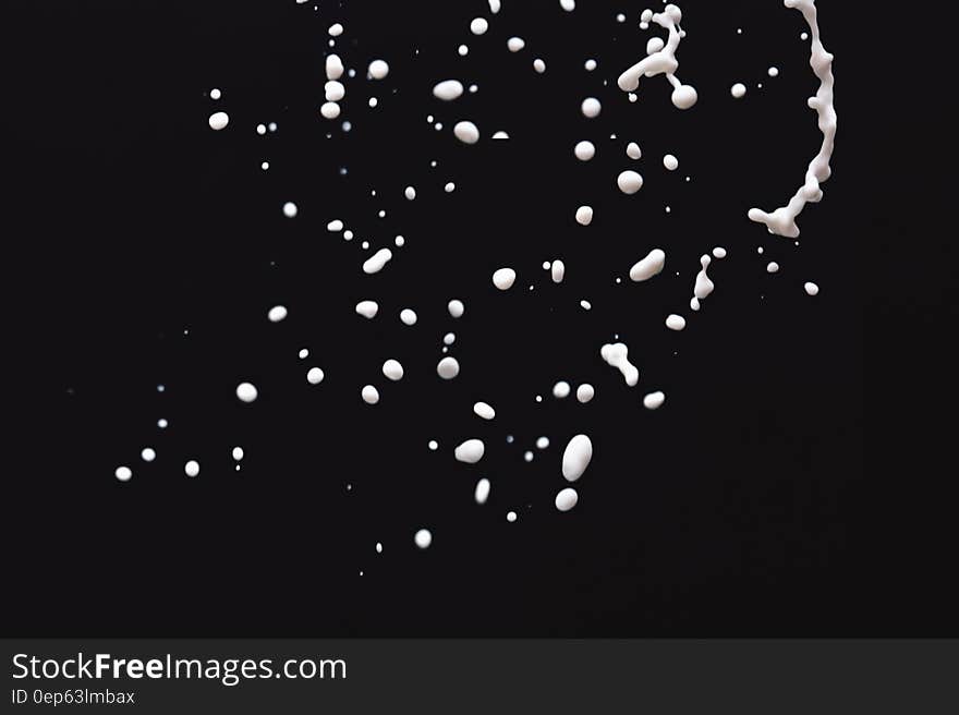 White milk droplets floating against black background. White milk droplets floating against black background.