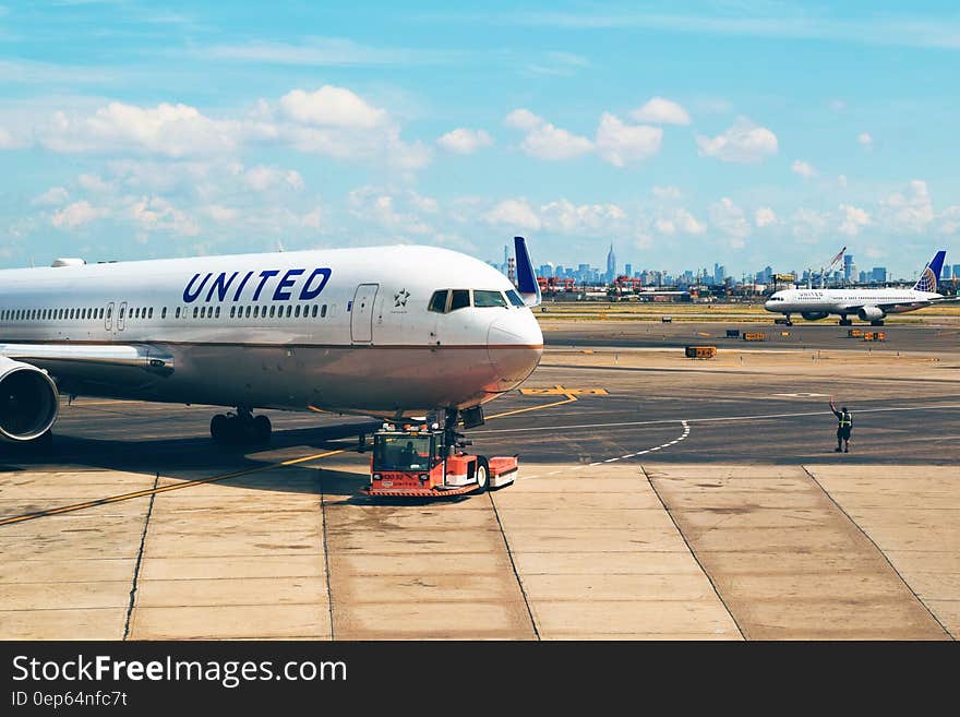 United Airlines plane being pushed from gate onto tarmac in airport on sunny day. United Airlines plane being pushed from gate onto tarmac in airport on sunny day.