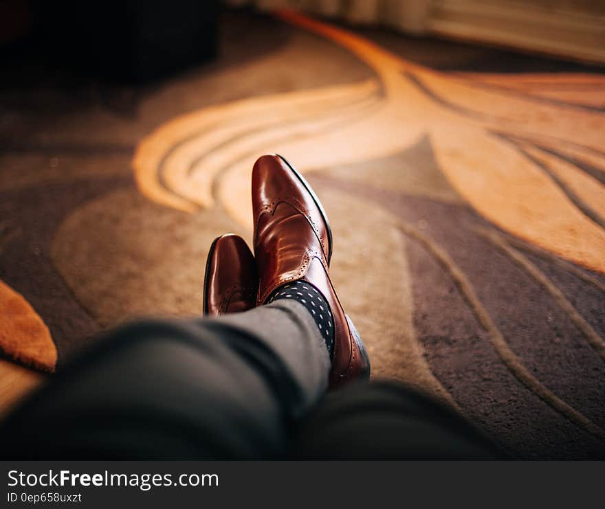 Close up of brown leather shoes on feet of mat resting on rug. Close up of brown leather shoes on feet of mat resting on rug.