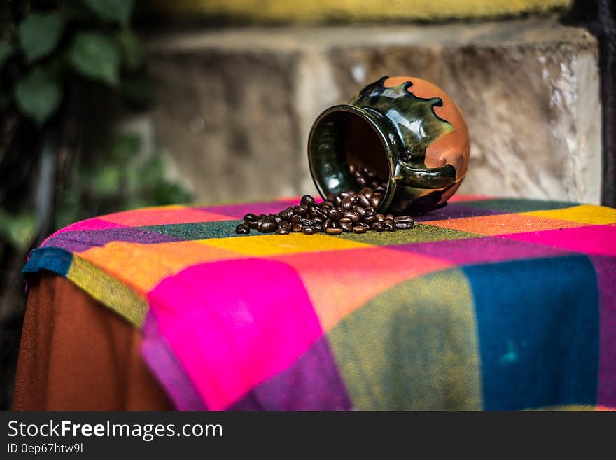 Brown and Black Ceramic Coffee Bean Rack on Pink Green and Yellow Textile