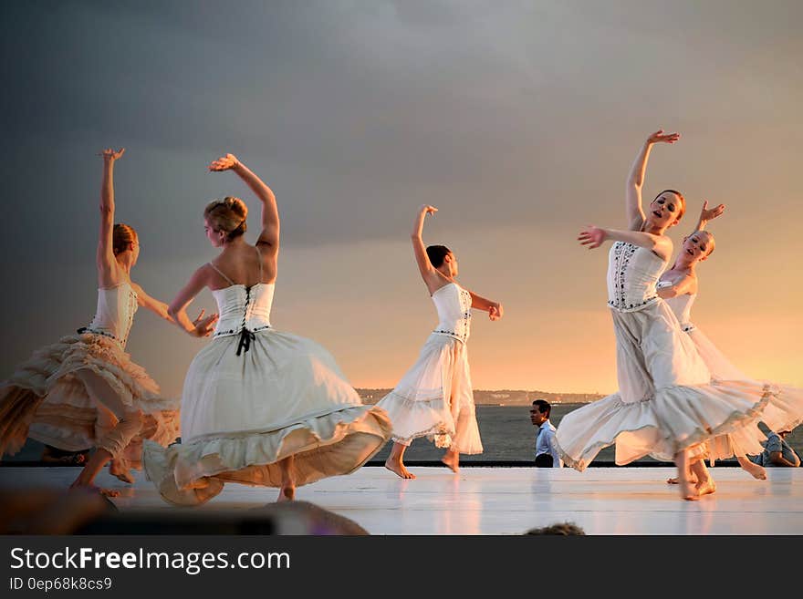 5 Women in White Dress Dancing Under Gray Sky during Sunset