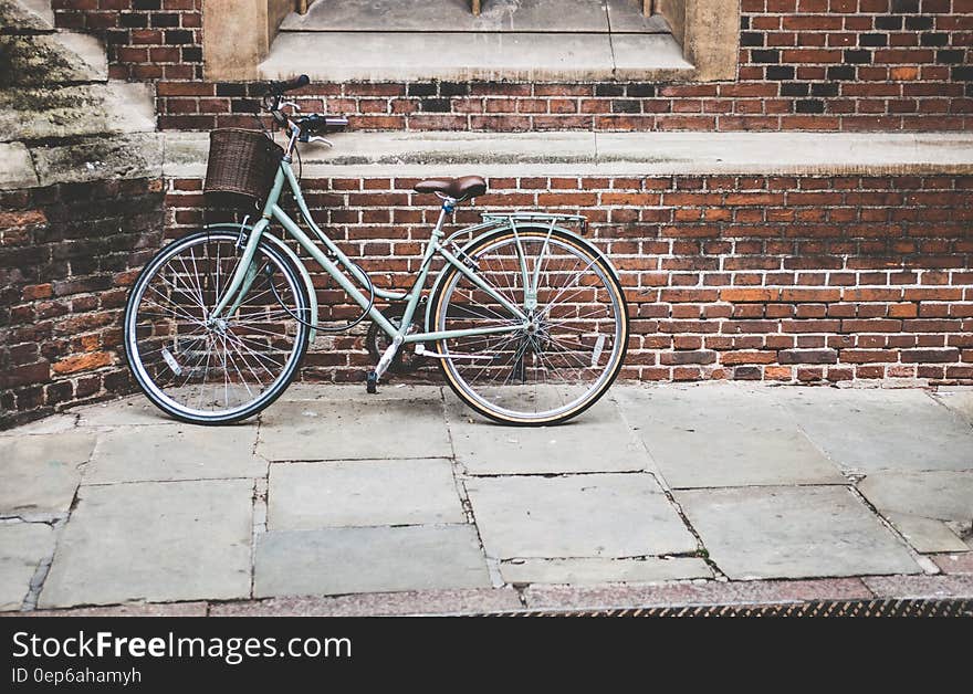 Blue Bicycle Parked on Brown Bricked Wall