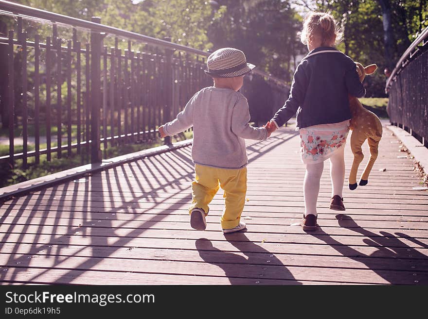 Boy and Girl Walking on Bridge during Daytime