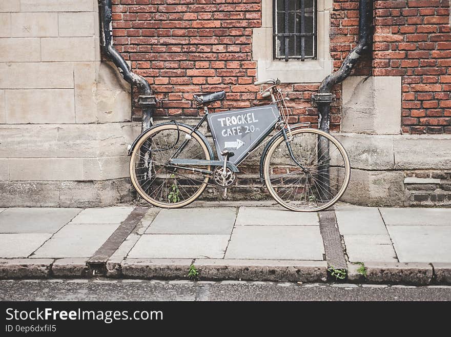 A bicycle with an advertisement leaning on a brick wall on a street. A bicycle with an advertisement leaning on a brick wall on a street.