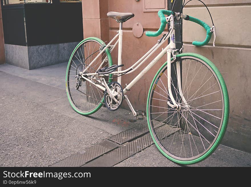 White and Green Bike Leaning on Wall