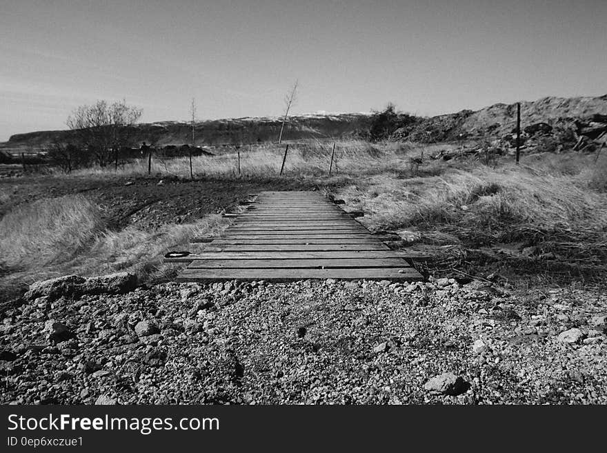 A black and white view of a small bridge crossing a stream. A black and white view of a small bridge crossing a stream.