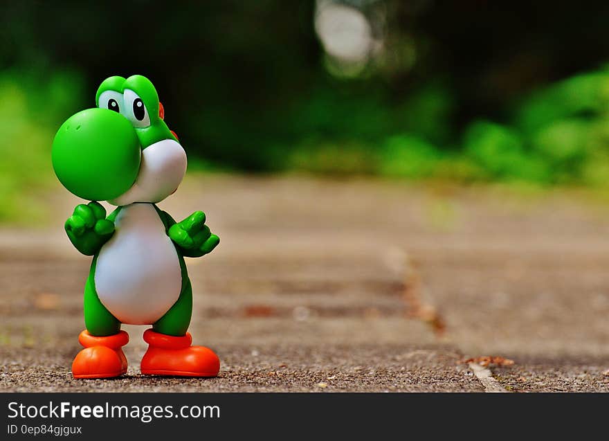 Green and White Dinosaur Toy on Brown Ground in Tilt Shift Photography