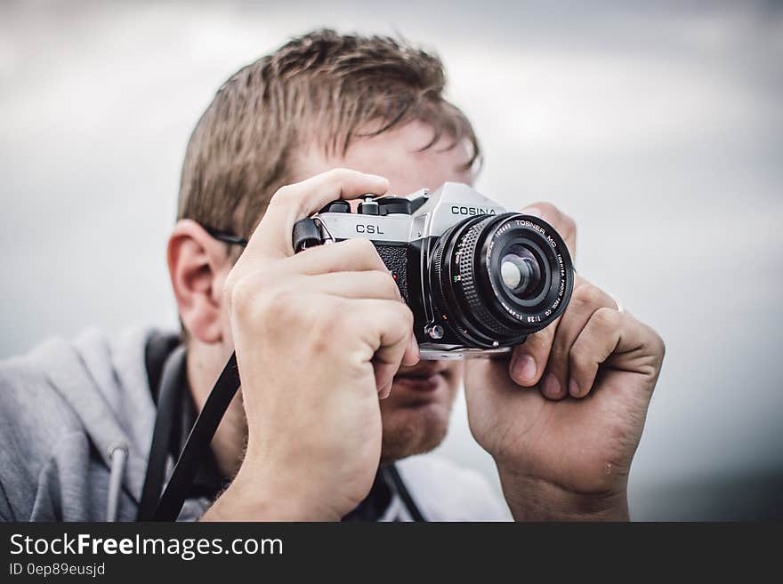 Man Holding Black Silver Bridge Camera Taking Photo during Daytime