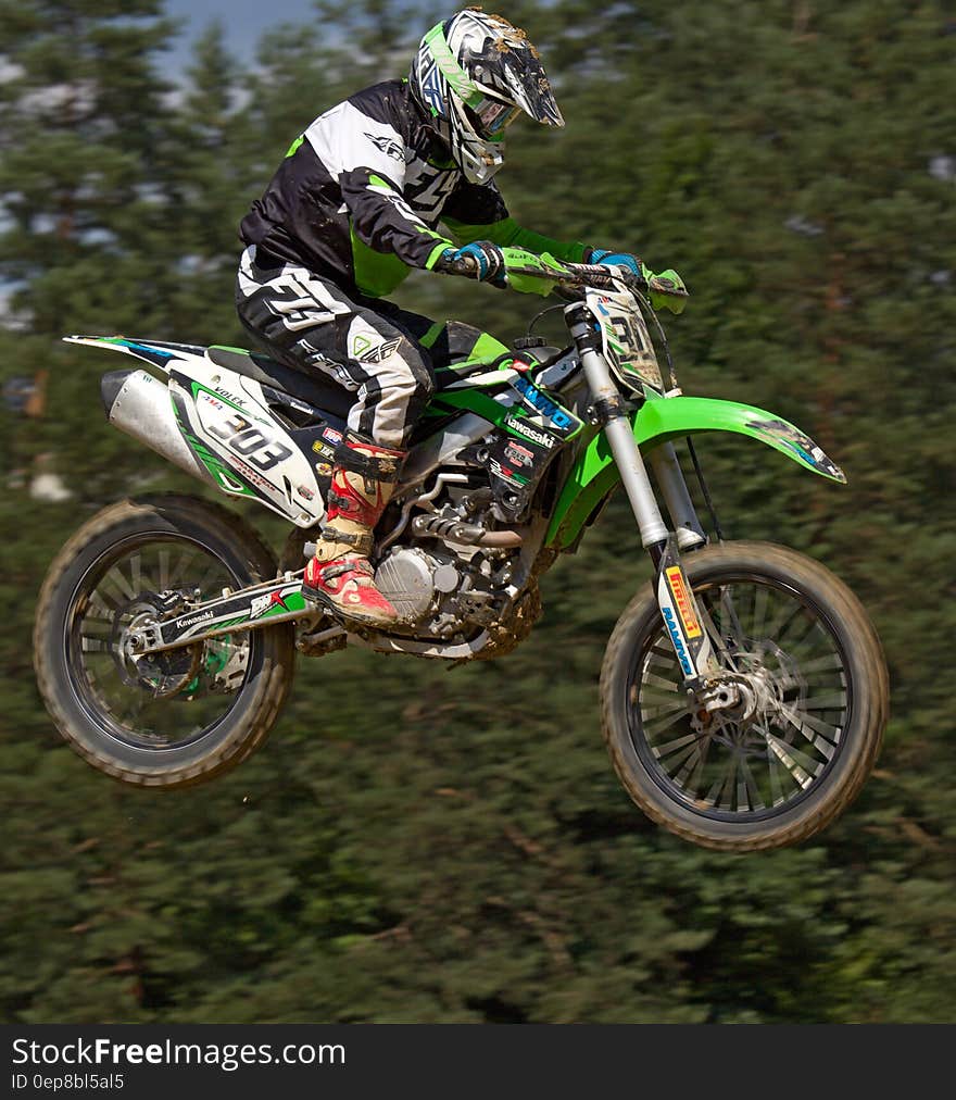 Man in Green White and Black Mtx Suit on Green and White 303 Dirt Motorcycle in the Air