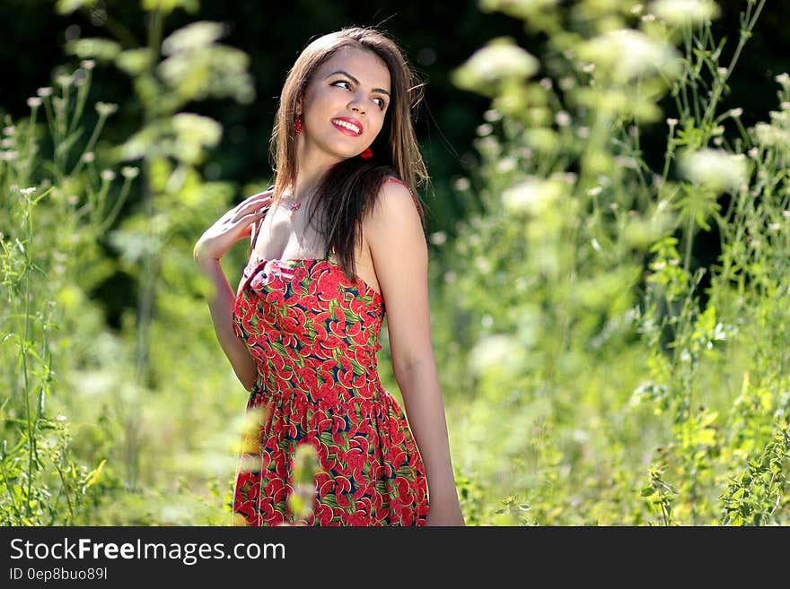 Smiling Woman in Pink Black and Green Floral Tube Dress Near Green Leaf Plants during Daytime