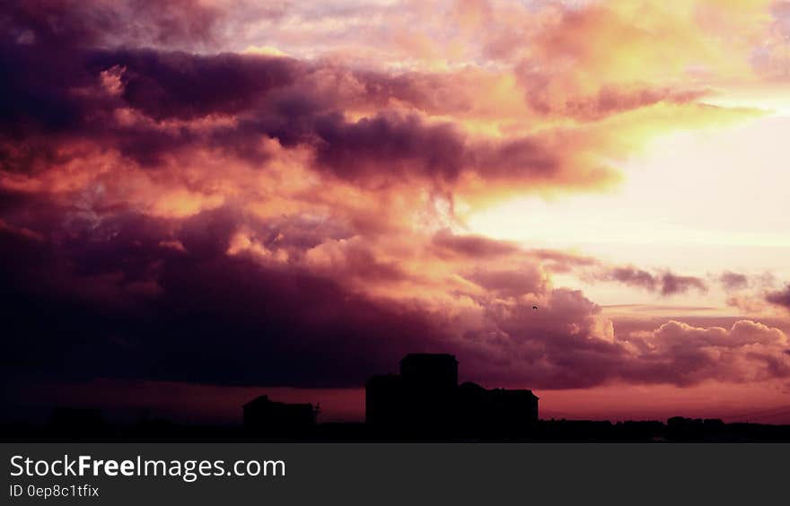 Colorful sunset and dark storm clouds over silhouetted building. Colorful sunset and dark storm clouds over silhouetted building.