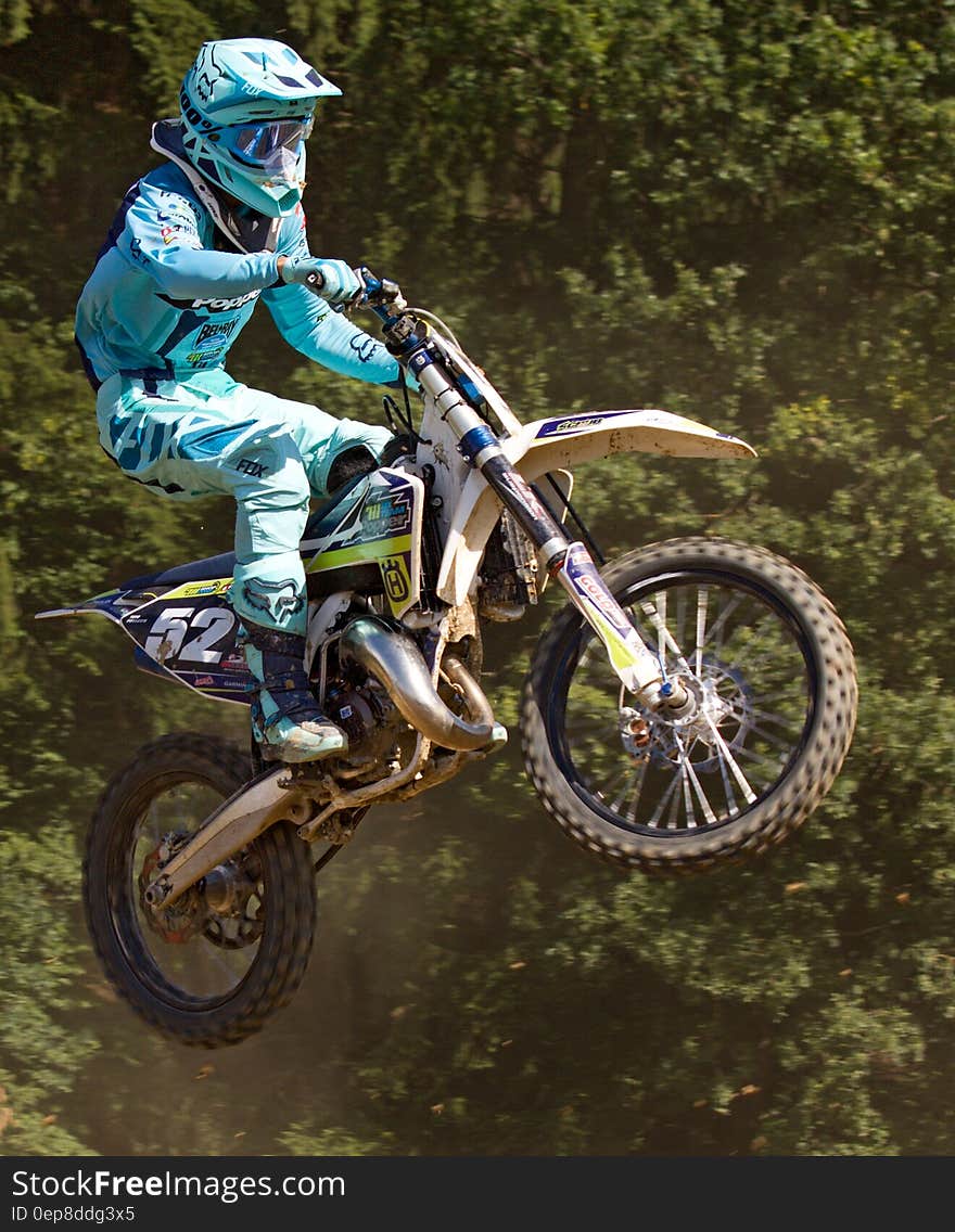 Man in Blue Mtx Suit Riding Blue and Yellow Dirt Motorcycle in Air