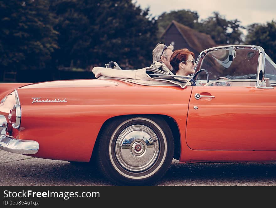 Couple Riding Red Ford Thunderbird during Daytime