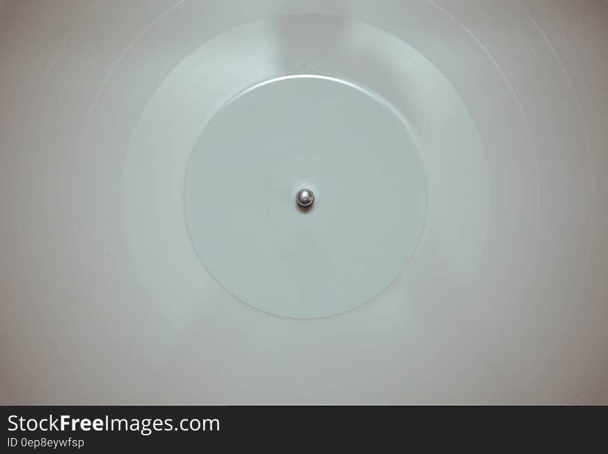 A white vinyl record on a record player, top view.