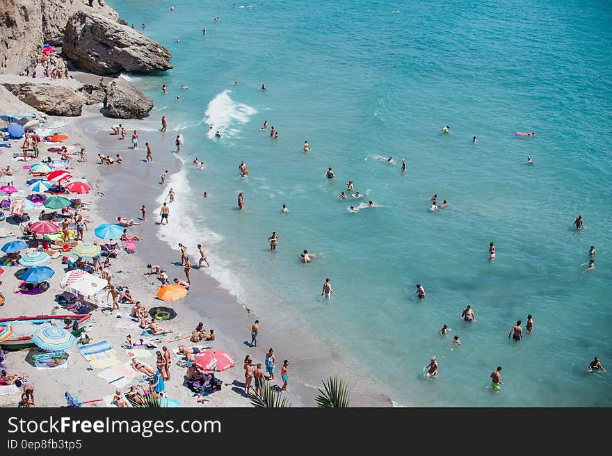 A seashore with sandy beach and people tanning and swimming.