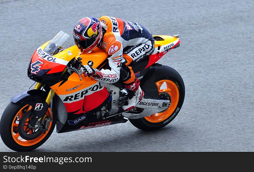 Man in Repsol Orange White and Blue Motorcycle Racing Gear Riding Sports Bike