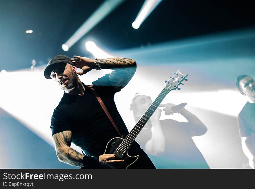 Man in Black Crew Neck Shirt Holding a Black Electric Guitar