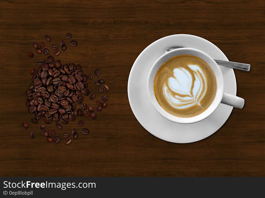 Brown and White Espresso in White Coffee Mug Beside Coffee Beans