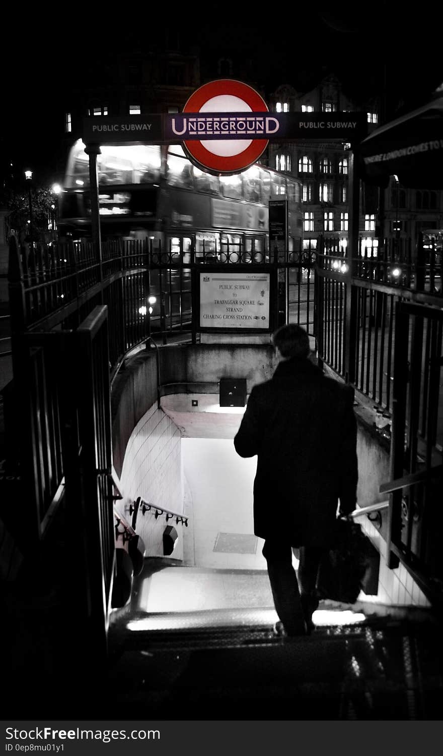 Rear view of businessman walking down steps to London underground metro station at night. Rear view of businessman walking down steps to London underground metro station at night.