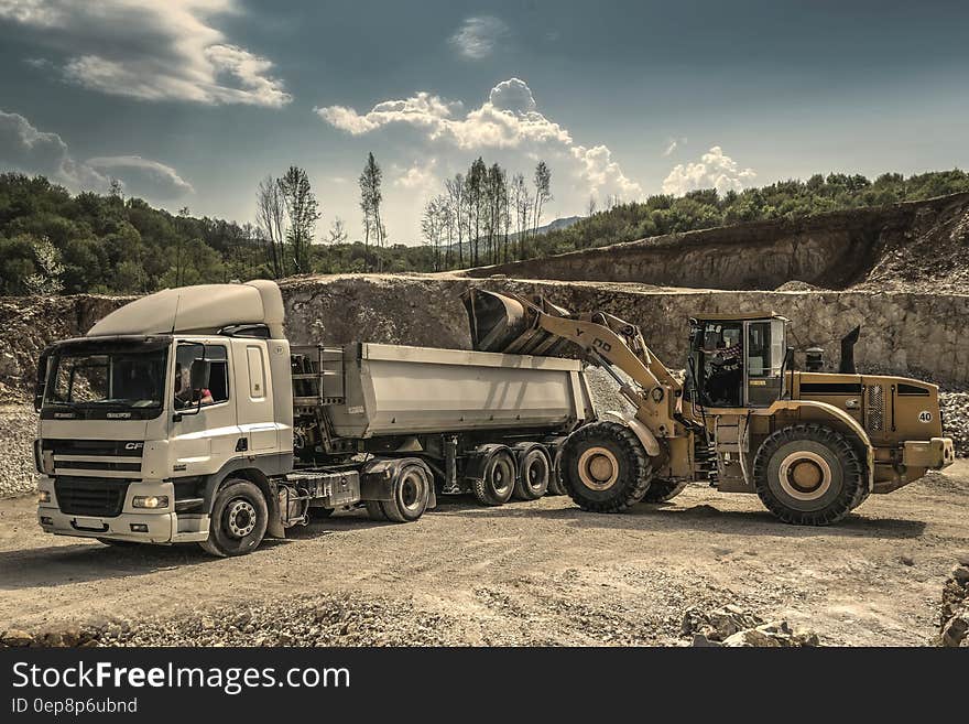 Front Load Loader Beside White Dump Truck