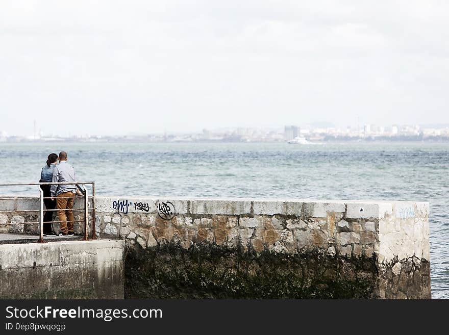 Man and Woman Standing Beside Dock Under Daylight