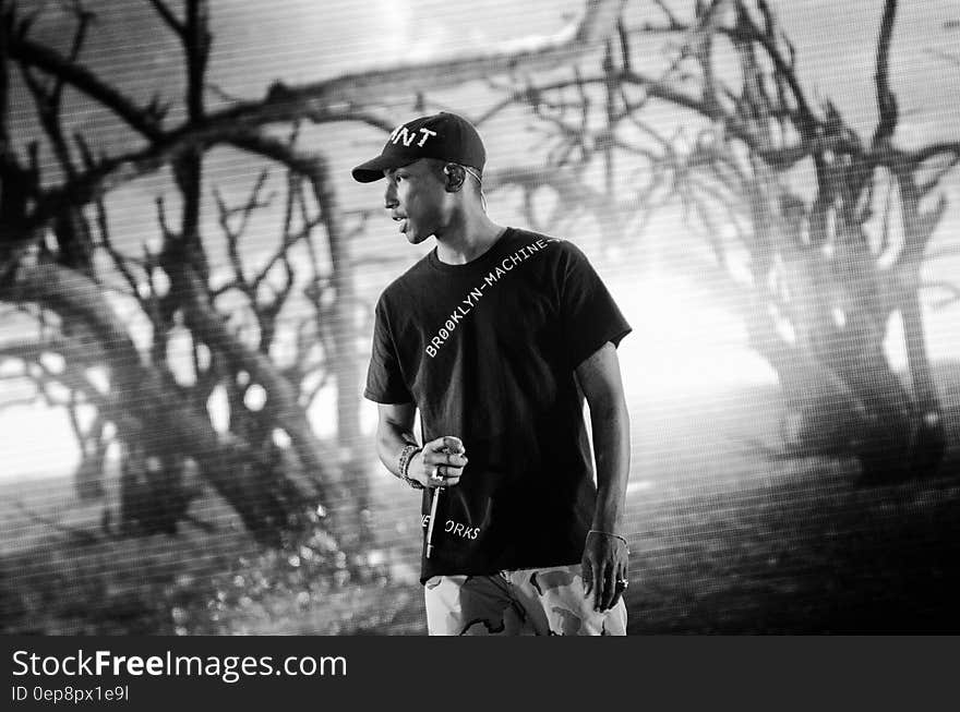 Grayscale Photo of a Person Near Leafless Trees