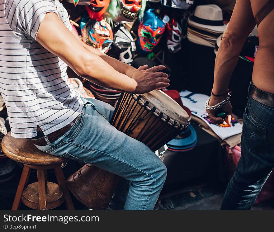 A player playing a traditional ceramic drum with skin in a marketplace. A player playing a traditional ceramic drum with skin in a marketplace.