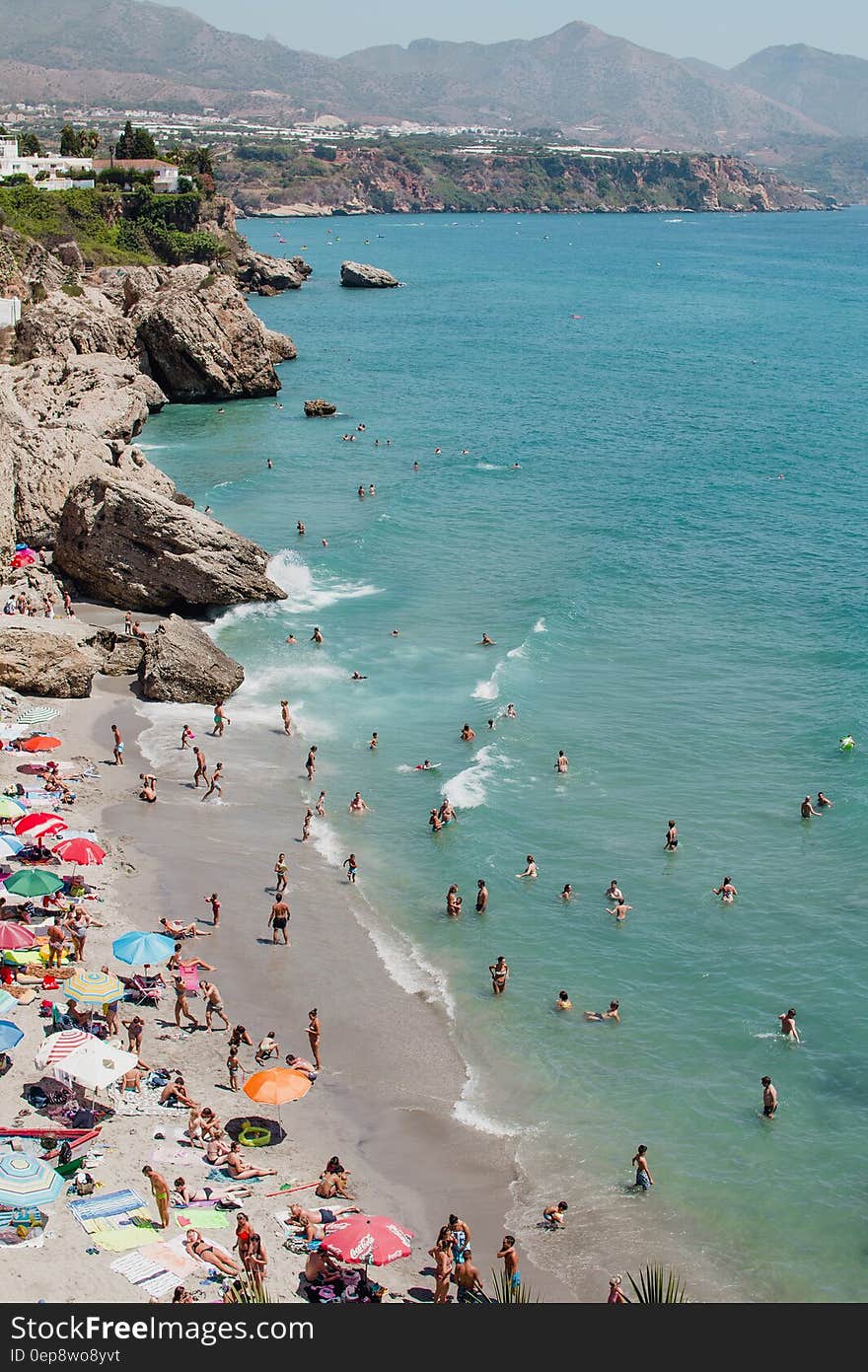 People Swimming on Ocean While Others Sunbathing