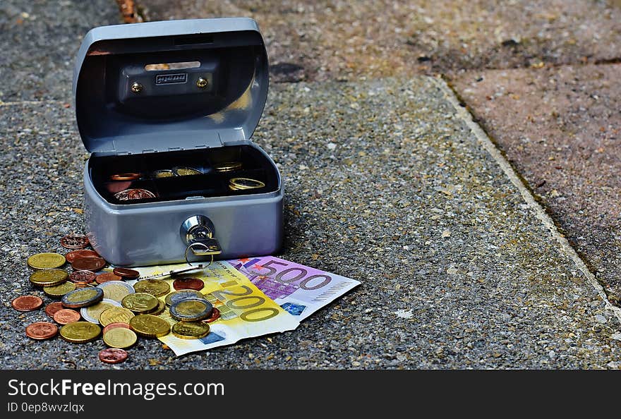 Open lock box on sidewalk outdoors with Euro bills and coins. Open lock box on sidewalk outdoors with Euro bills and coins.