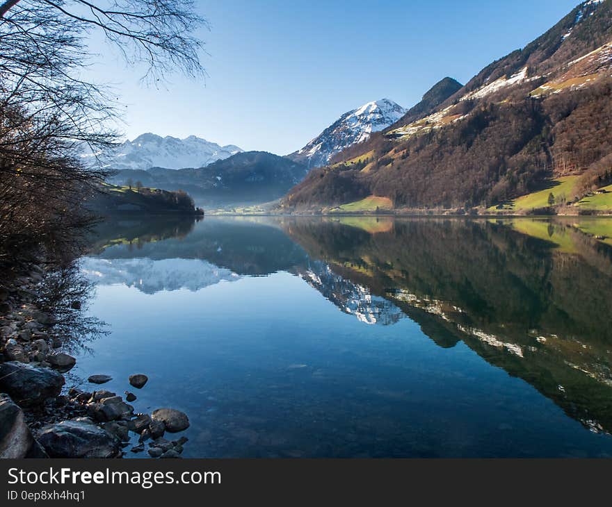 Mountain peaks reflected in still waters of alpine lake on sunny day. Mountain peaks reflected in still waters of alpine lake on sunny day.