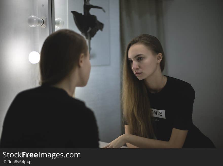 Woman in Black Shirt Facing Mirror