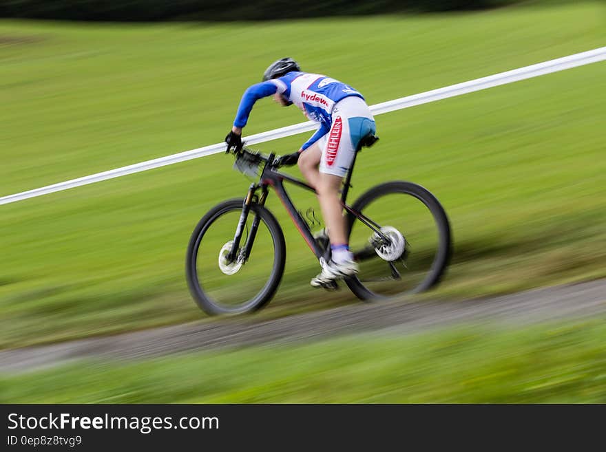 Man in Blue and White Long Sleeve Sweat Shirt Riding Black Hard Tail Bicycle