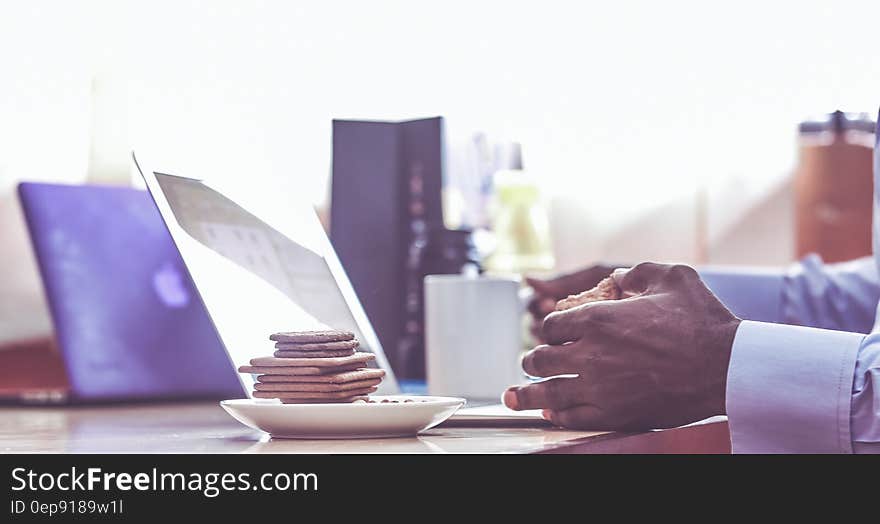 Man Leaning on Table With Piled Crackers on White Saucer