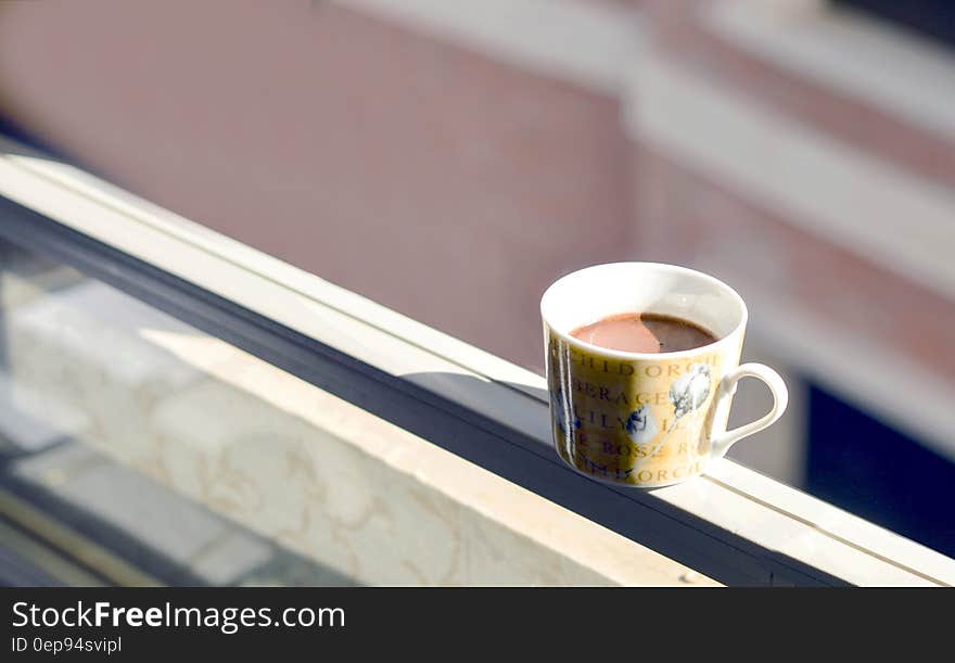 Coffee in White and Yellow Ceramic Mug on White Surface