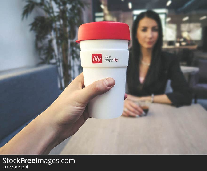 Person Holding White and Red Live Happilly Cup