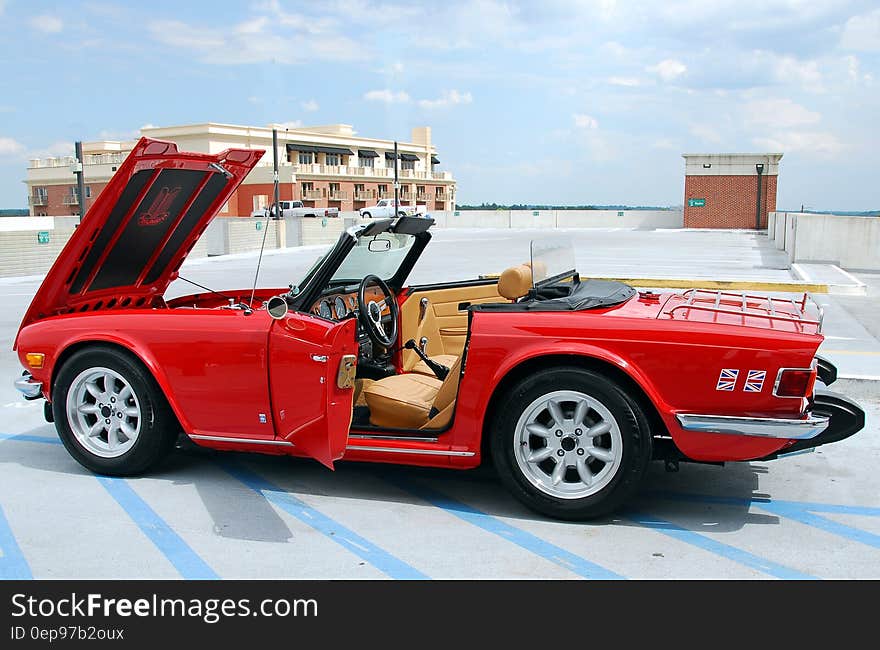 Red convertible sport scar on parking garage roof with hood and doors open. Red convertible sport scar on parking garage roof with hood and doors open.