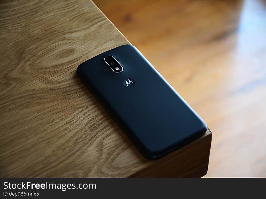 Black Motorola Smartphone on Top of Brown Wooden Table