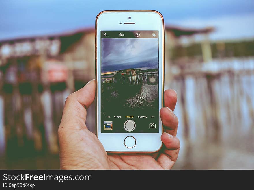 Picture Holding Iphone Taking Photo on House on Beach