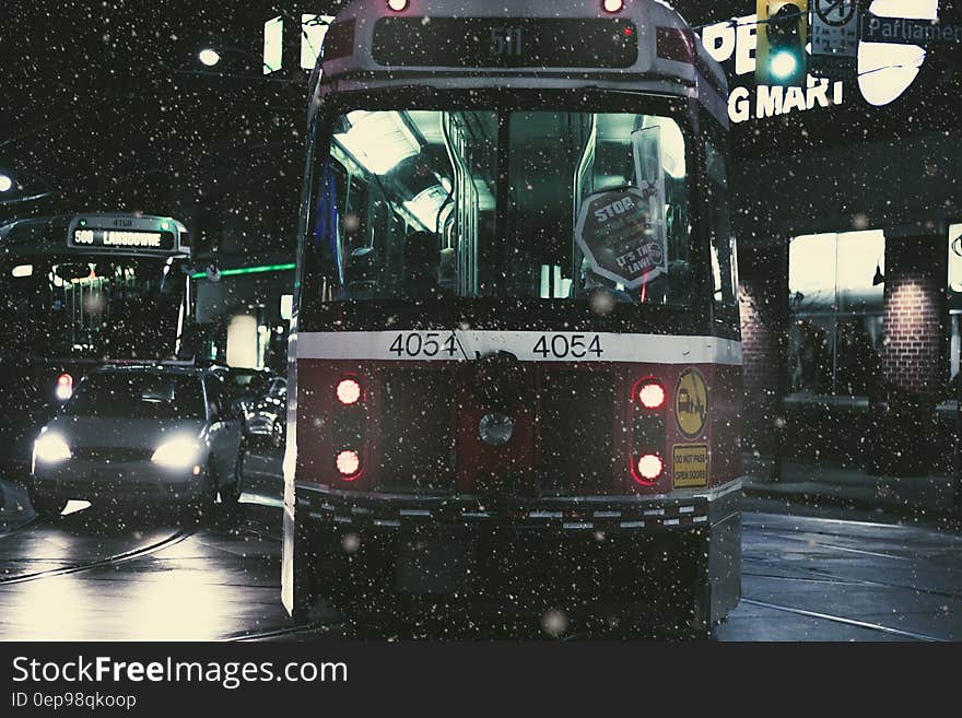 Train on Road Beside Cars during Nighttime