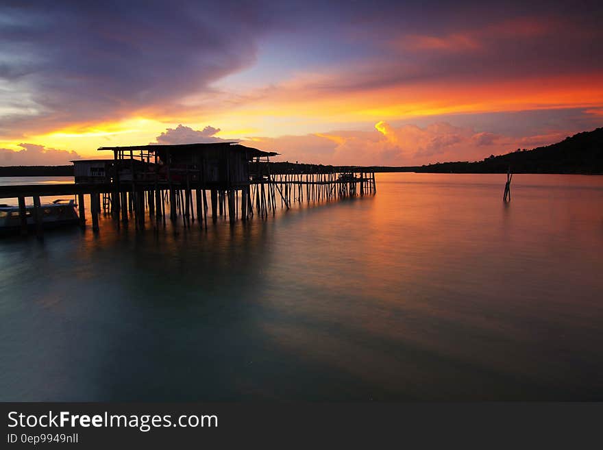 Silhouette of Wooden House Above Sea during Sunset