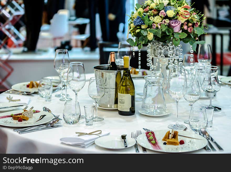 White Labeled Bottle Near Clear Glass Wine Bottle on White Round Table