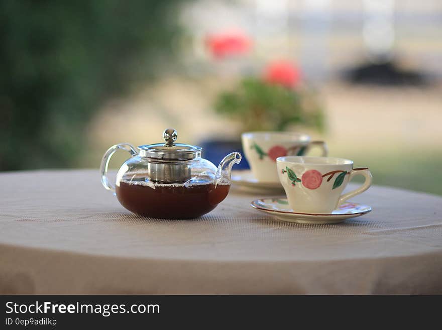 Pot of tea and two tea cups on garden table. Pot of tea and two tea cups on garden table.