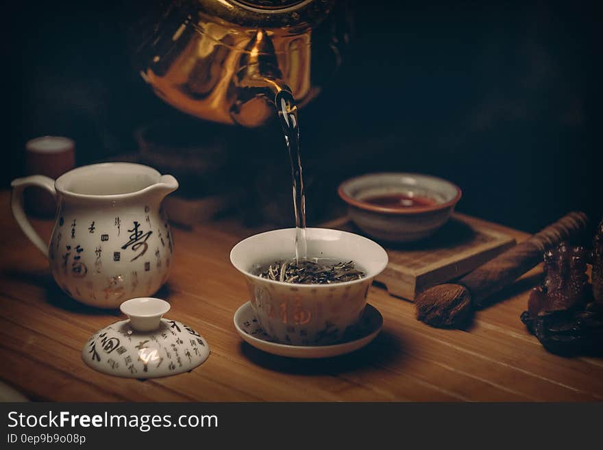 Gold Kettle Pouring Hot Water on Cup of Tea