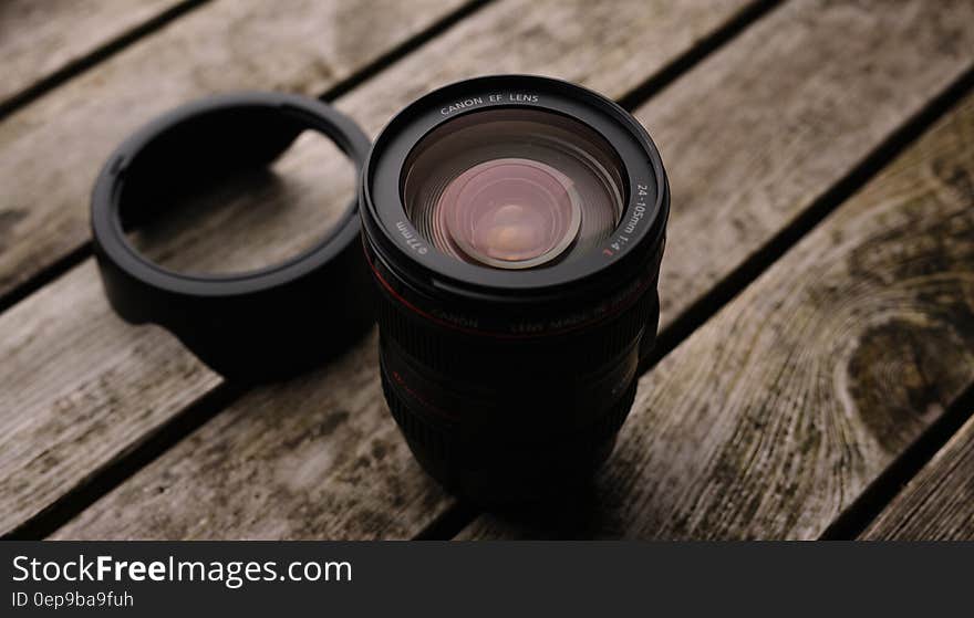 Black Dslr Camera Lens With Lid on Wooden Platform