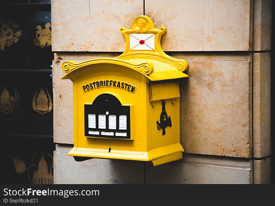 Yellow Postbriefkasten Floating Mailbox on Brown Concrete Wall