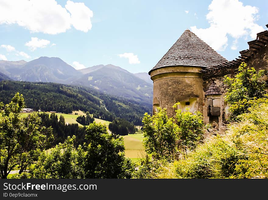 Brown Concrete House Beside Green Tree and Far Mountain on Daytime