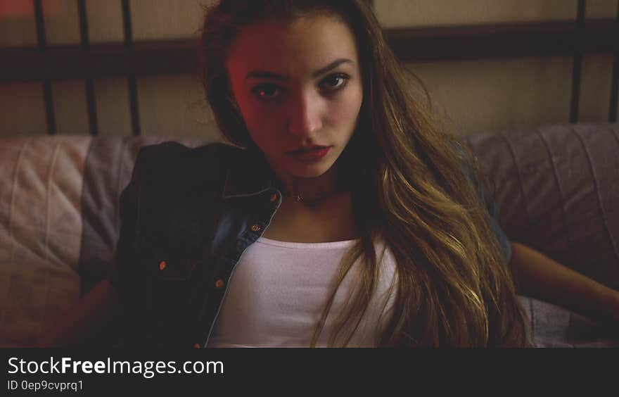 Woman in Blue Denim and White Shirt Sitting Inside Brown Painted Room