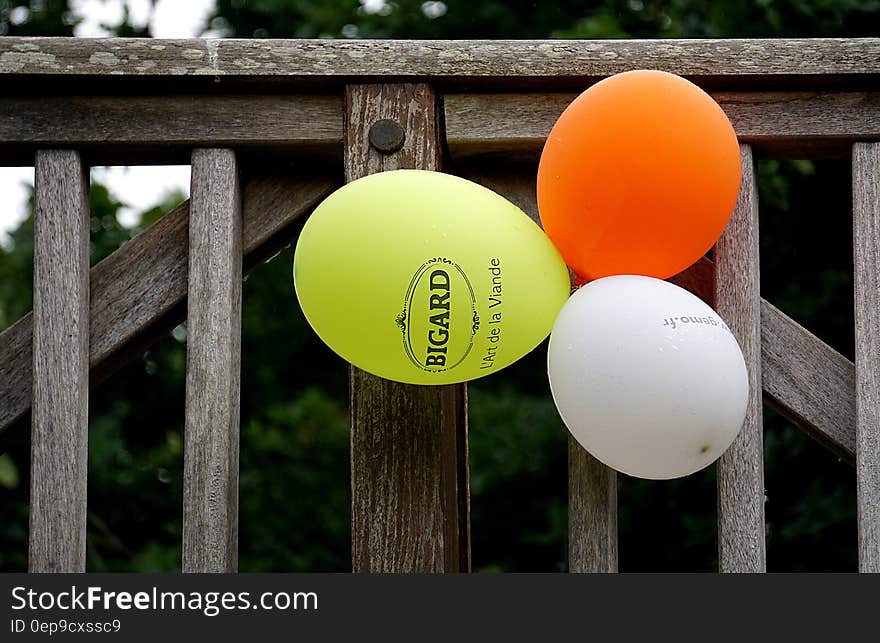 Yellow Orange and White Balloon Beside Gray Wooden Fence