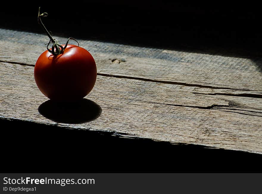 Red ripe whole tomato on worn wooden plank in sunlight. Red ripe whole tomato on worn wooden plank in sunlight.